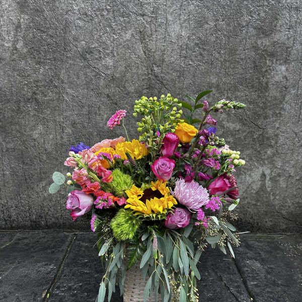 Colorful mixed flower arrangement in a woven basket