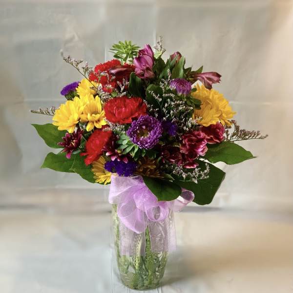 Colorful mixed bouquet in a clear glass vase with a lavender ribbon