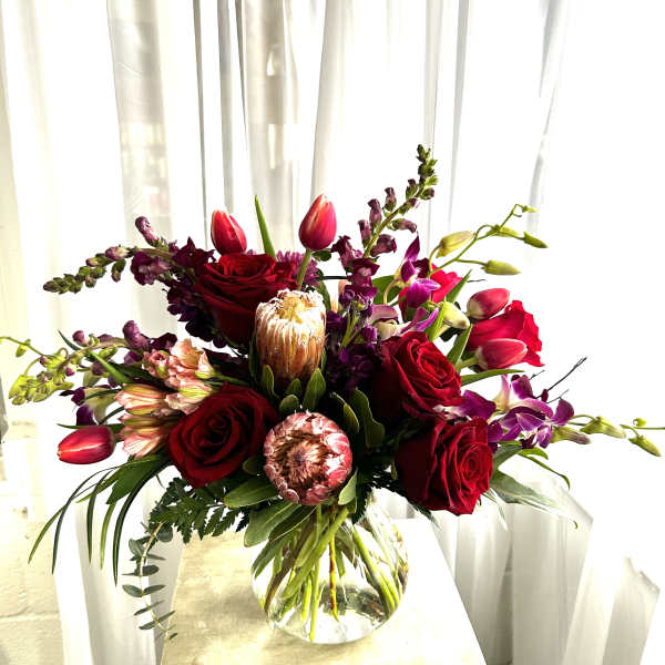 Red roses and pink tulips in a clear glass vase