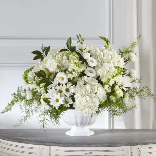 White floral arrangement in a white pedestal vase