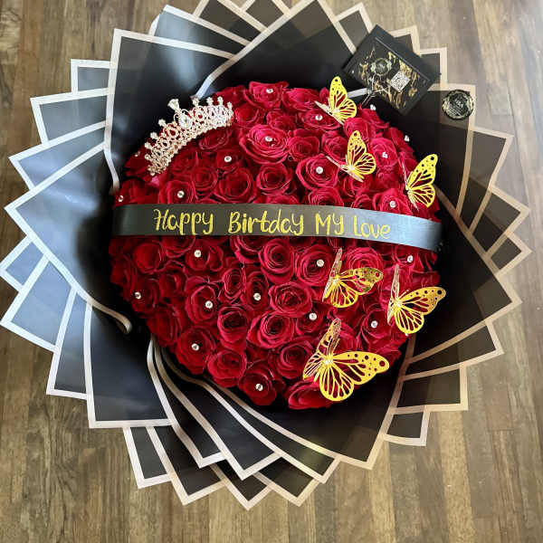 Round bouquet of red roses with a birthday ribbon and butterfly decorations