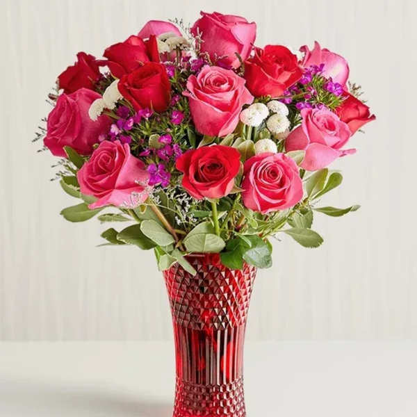Bouquet of red and pink roses in a red glass vase