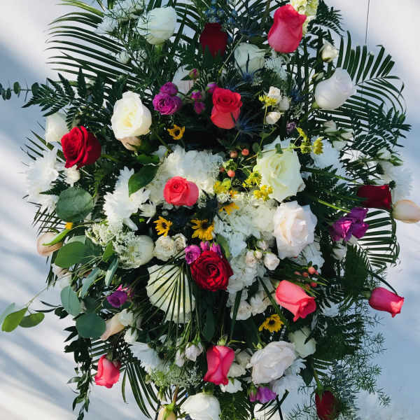 Large standing floral spray with roses, white blooms, and greenery