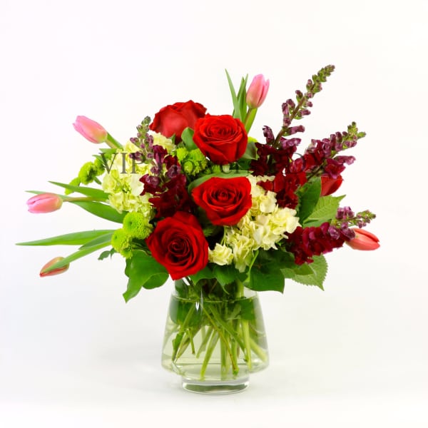 Red roses and pink tulips in a clear glass vase
