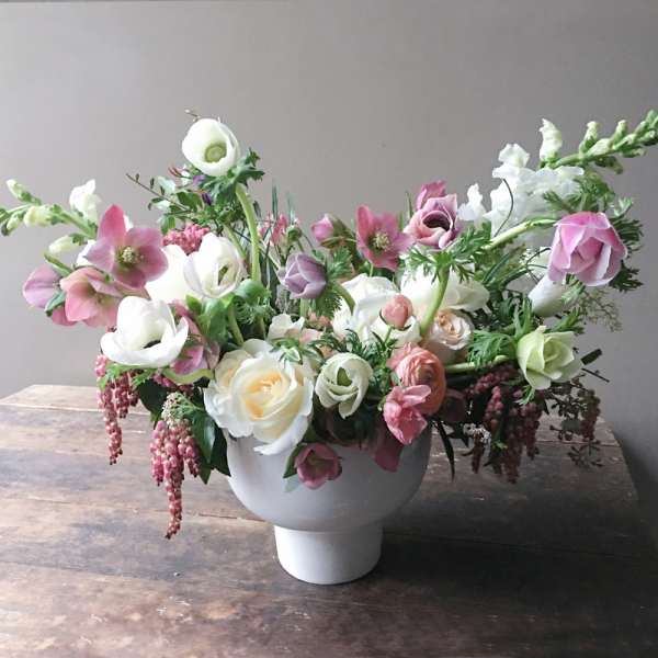 Pink and white floral arrangement in a white pedestal vase