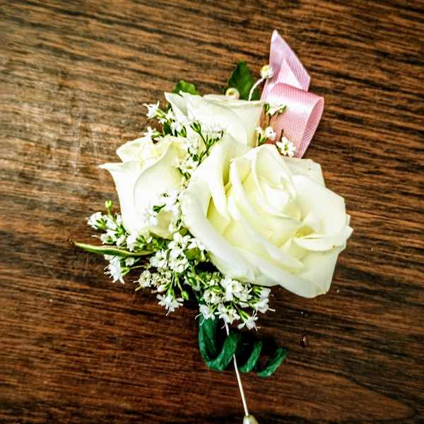 White rose boutonniere with pink ribbon and pearl pin