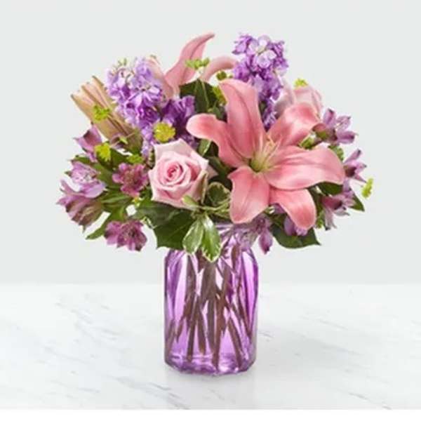 Pink lilies and roses in a purple glass vase