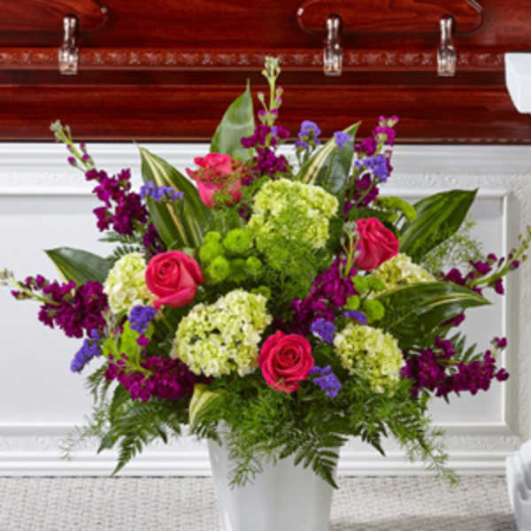 Pink roses and purple flowers arranged in a white vase