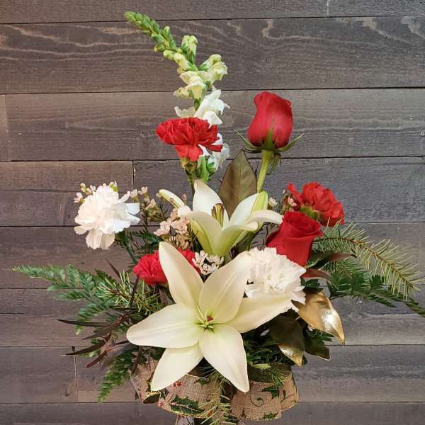 Red roses and white lilies in a glass vase with carnations