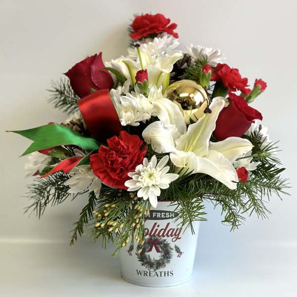 Holiday bouquet with red and white flowers in a festive bucket