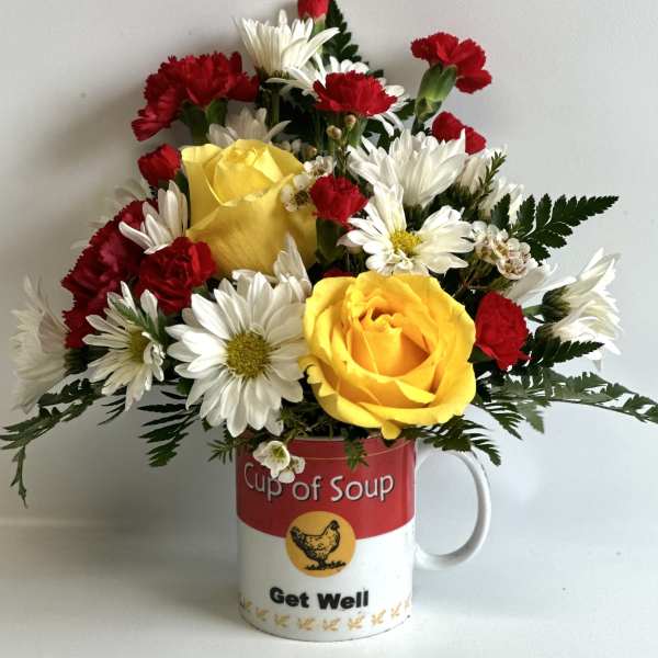 Bouquet of yellow roses, white daisies, and red carnations in a soup mug