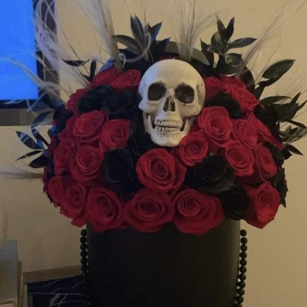 Black hatbox arrangement with red roses and a skull topper