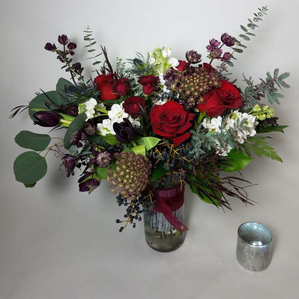Bouquet of red roses and dark purple flowers in a glass vase