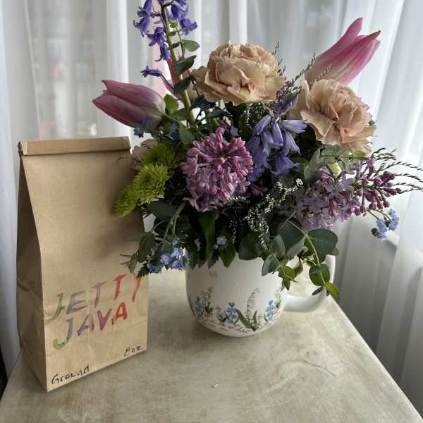 Mixed bouquet in a floral mug beside a paper gift bag