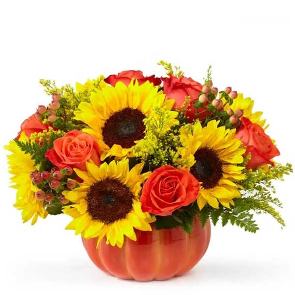 Sunflowers and red roses arranged in an orange pumpkin vase
