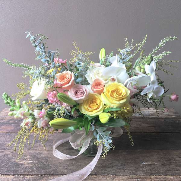 Pastel bouquet of roses, lilies, and orchids in a glass vase