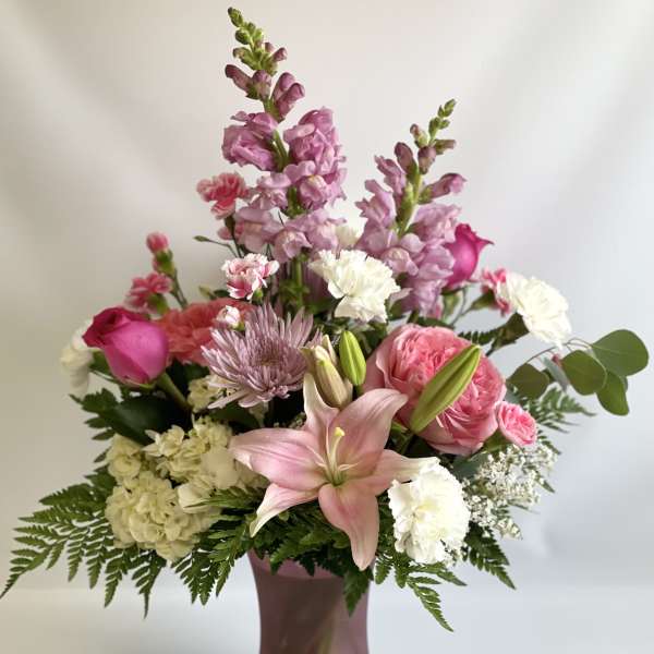 Pink and white mixed flower arrangement in a mauve vase