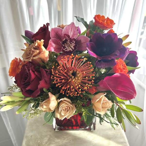 Colorful bouquet with roses, orchids, and calla lilies in a glass vase