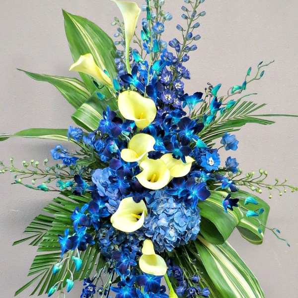 Tall blue and yellow floral standing arrangement with calla lilies