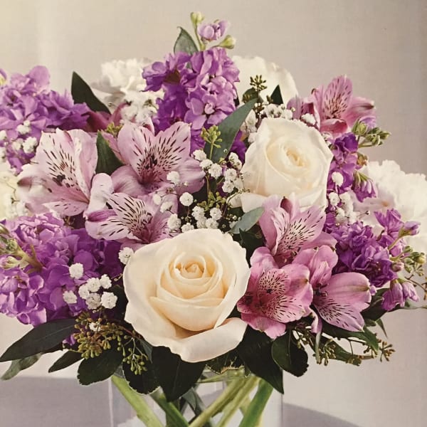 Bouquet of white roses and pink-purple flowers in a glass vase
