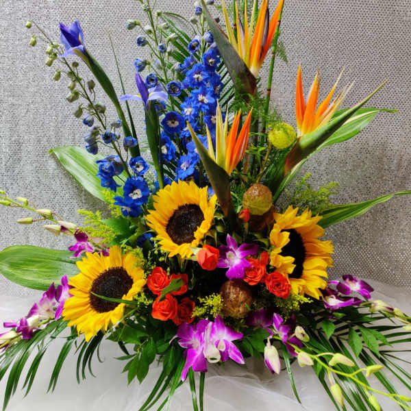 Colorful tropical bouquet with sunflowers, orchids, and blue flowers