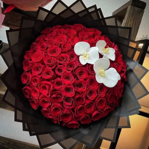 Round bouquet of red roses with white orchids in black wrap