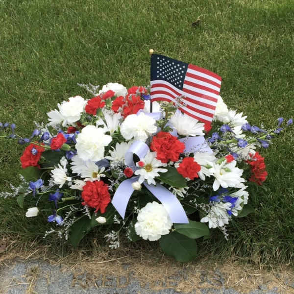 Red, white, and blue floral grave arrangement with an American flag