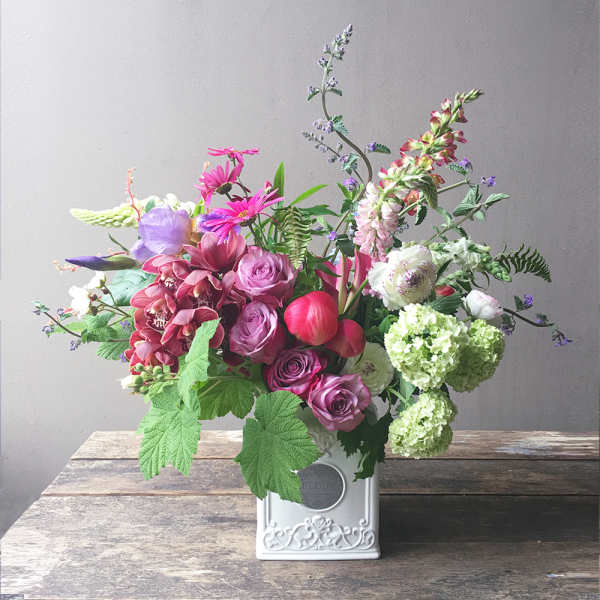 Mixed bouquet of pink, purple, and white flowers in a white vase