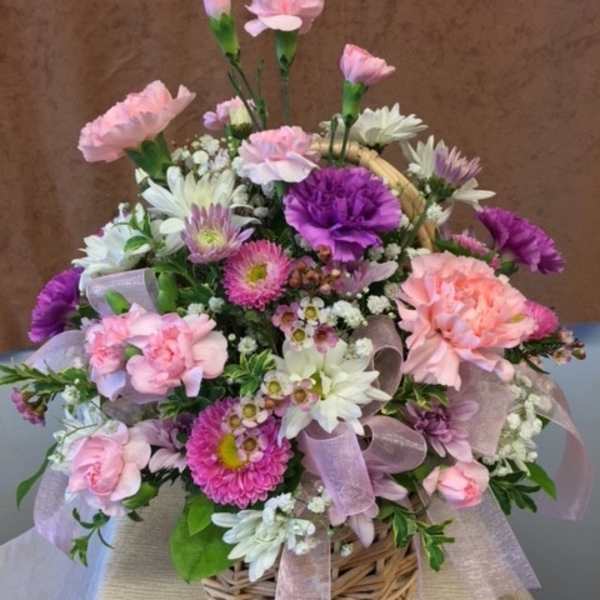 Basket arrangement of pink, purple, and white flowers with a ribbon