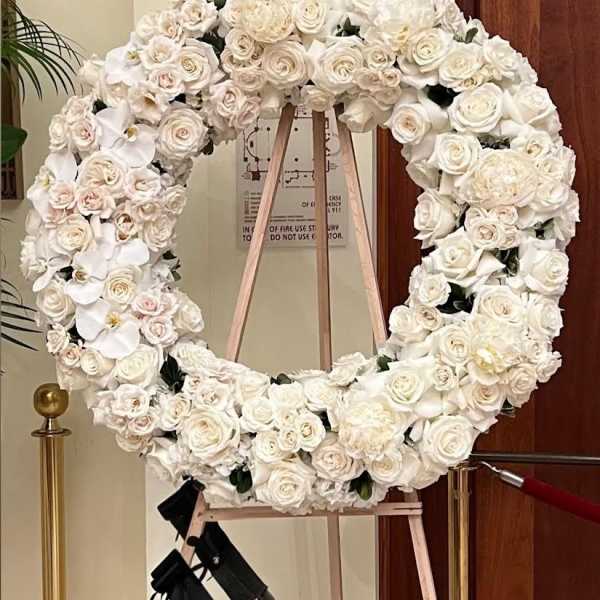 Large white floral wreath on a wooden easel