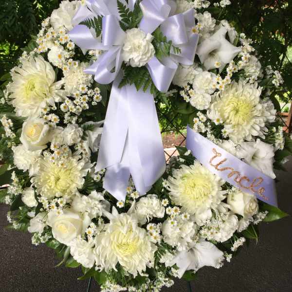 White funeral wreath with lavender ribbon and mixed white flowers
