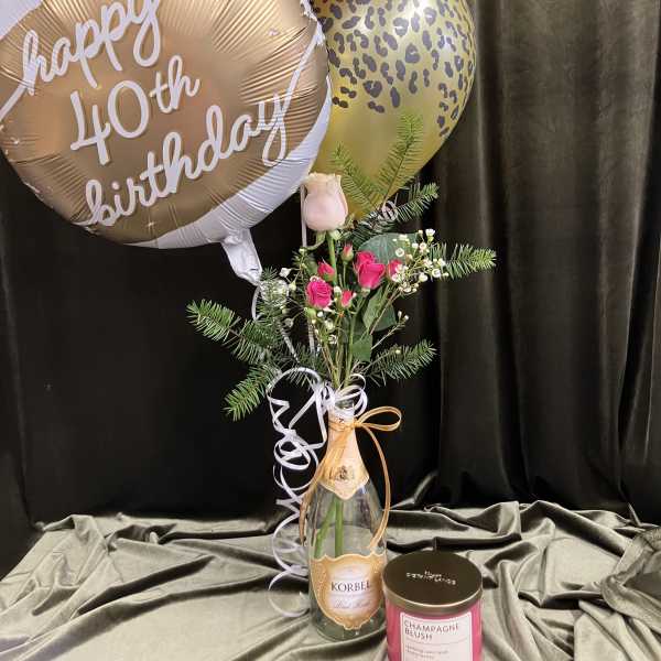 Birthday balloons with a small pink rose arrangement in a bottle vase