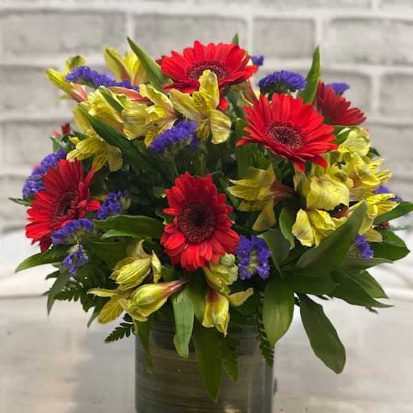 Bouquet of red gerbera daisies and yellow alstroemeria in a glass vase