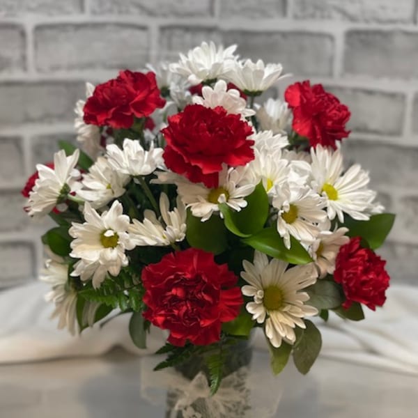 Bouquet of red carnations and white daisies in a glass vase
