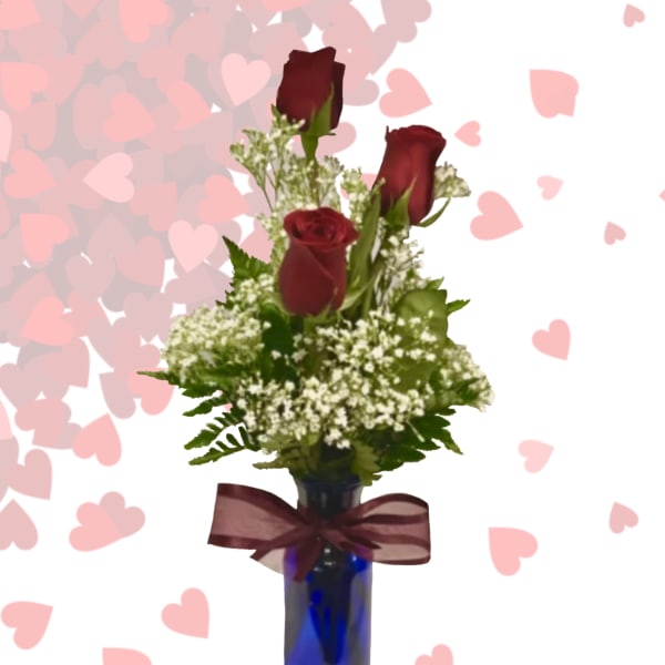 Three red roses in a blue vase with a burgundy ribbon