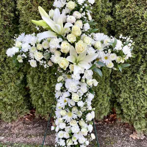 White floral cross standing on a metal easel