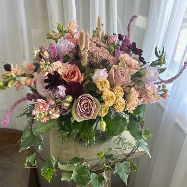 Mixed bouquet of roses, carnations, and small blooms in a glass vase