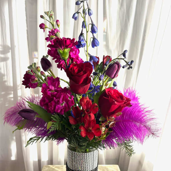 Bright mixed bouquet in a rhinestone vase with red roses and purple flowers