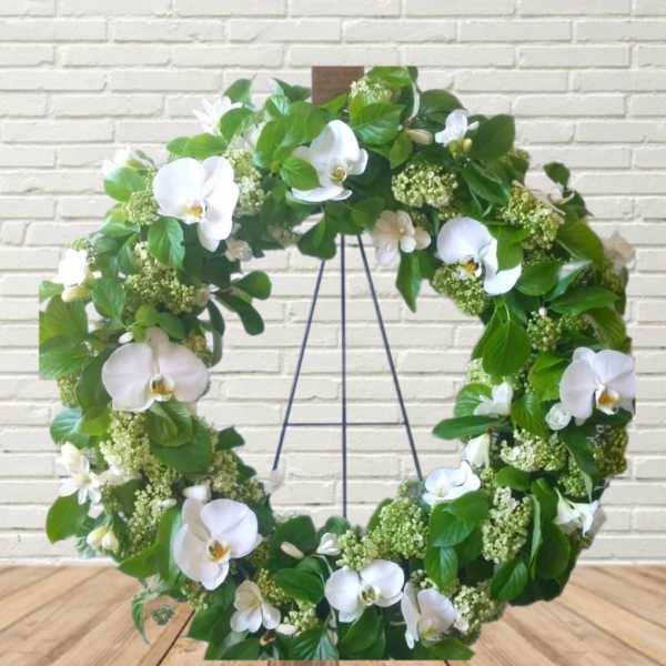 White orchid wreath with green foliage on a stand