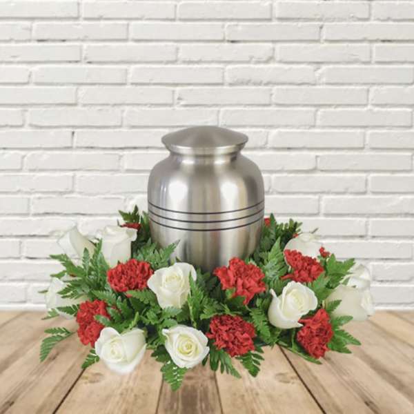 White roses and red carnations arranged around a silver urn