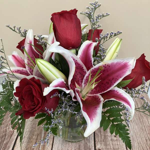 Red roses and pink stargazer lilies in a glass vase