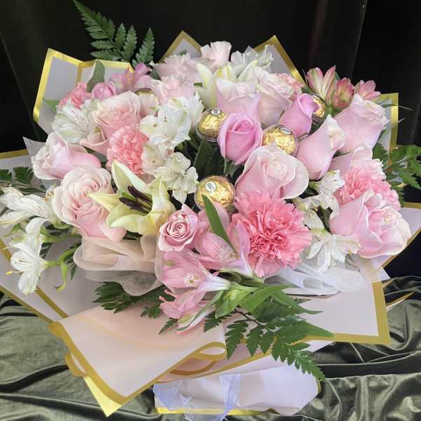 Pink and white bouquet with roses, lilies, and carnations wrapped in gold-trimmed paper