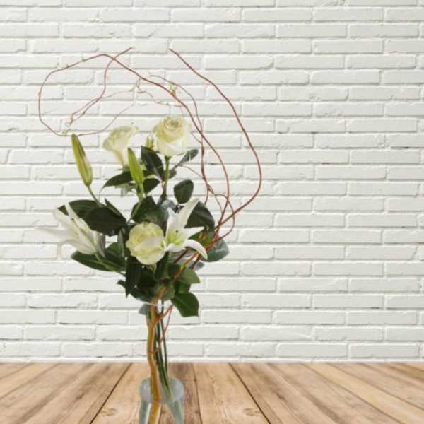 Tall bouquet of white roses and lilies in a clear vase