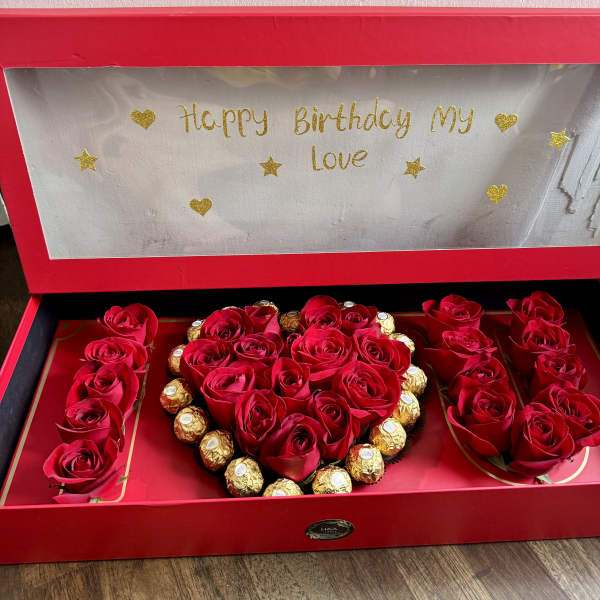 Red roses and chocolates arranged in a heart-shaped gift box