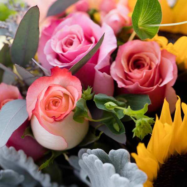 Bouquet of pink roses with yellow sunflowers and gray-green foliage