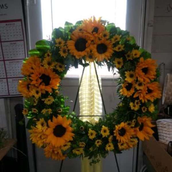 Large sunflower wreath on a stand with a yellow ribbon