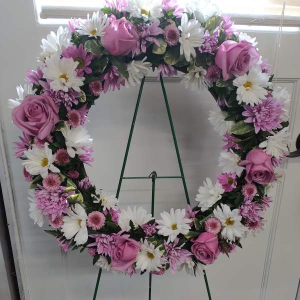 Pink and white floral wreath on a green easel stand