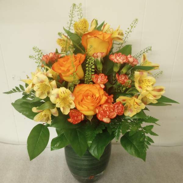 Orange roses and yellow alstroemeria in a dark vase