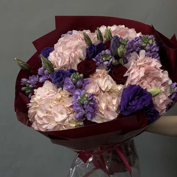 Bouquet of pink, purple, and red flowers wrapped in burgundy paper