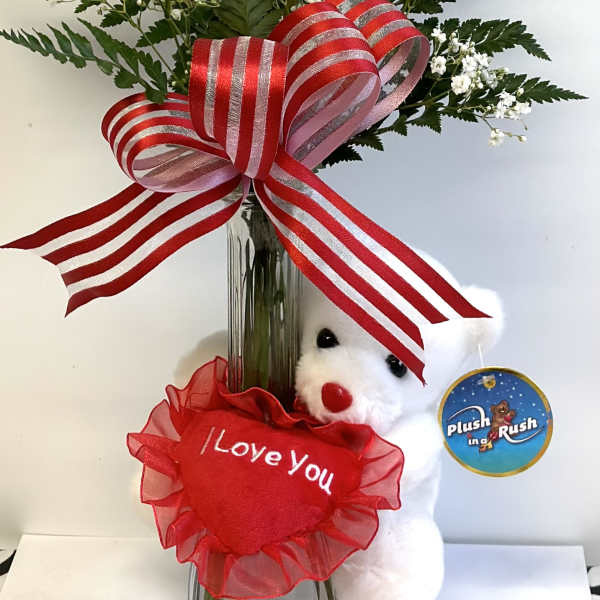 Single red rose in a glass vase with a teddy bear and ribbon bow